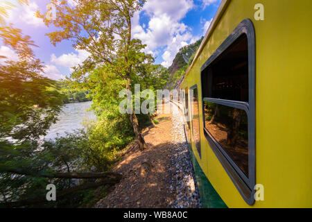 Train, vue depuis une fenêtre. Vieux train passant de la végétation verte. Vue de la fenêtre. Voyager en train au coucher du soleil. Paysage au coucher du soleil et un train gil Banque D'Images