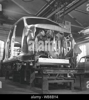 La production des automobiles dans les années 40. Un ouvrier d'une chaîne de montage automobile utiliser un outil hydraulique à assembler les pièces de la voiture ensemble. Après la seconde guerre mondiale, plusieurs sociétés en Suède a reçu des voitures en pièces détachées et assemblée. C'était moins cher d'importer des pièces de voiture puis l'ensemble de la voiture. Suède 1948. Kristoffersson ref AP89-2 Banque D'Images