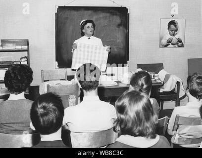 Apprendre à avoir un bébé dans les années 60. Une infirmière je debout devant un groupe de parents à l'apprentissage, leur parler de choses pratiques quand besoin de savoir une fois qu'ils ont des enfants de leurs propres. Mars 1964. Banque D'Images