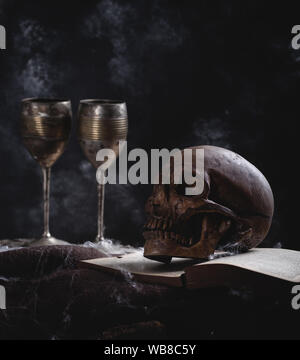 Effrayant crâne humain sur un vieux livre sur un fond sombre, concepy Halloween Banque D'Images