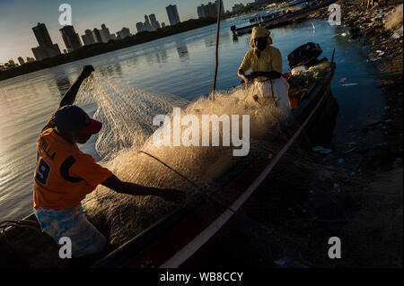 Les pêcheurs d'Afro-Colombiens enroulez le filet de pêche pendant le crépuscule dans le marché d'Bazurto à Cartagena, Colombie. Banque D'Images