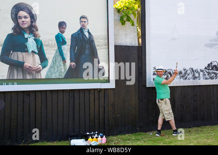 Bournemouth, Dorset UK. 25 août 2019. L'artiste britannique David Downes a été commandé par ITV pour créer une murale de grande envergure pour lancer leur nouveau drame Sanditon, basé sur le roman inachevé par Jane Austen. La peinture murale de la ville fictive de Sanditon sera de 12 mètres de large et est peinte sur 5 jours à partir d'aujourd'hui avant le premier épisode de Sanditon à la télévision ce soir, la murale sera ensuite sur l'écran pendant 3 semaines. Credit : Carolyn Jenkins/Alamy Live News Banque D'Images