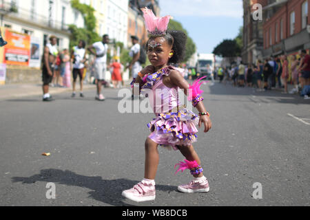 Une jeune danseuse exécute pendant la journée des enfants lors de la parade du carnaval de Notting Hill dans l'ouest de Londres. Banque D'Images