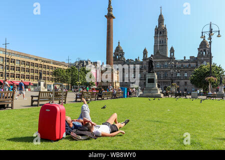 Glasgow, Ecosse, Royaume-Uni. 25 août 2019. Que les températures montent à plus de 26C à Glasgow après des jours de pluie et vent froid, les gens affluent vers les espaces ouverts de la ville de George Square et du Jardin botanique pour profiter de la fin de l'été soleil sur cette banque août vacances, pour parfaire votre bronzage et vous détendre. Credit : Findlay/Alamy Live News Banque D'Images