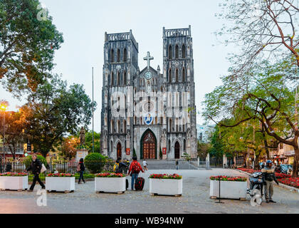 Hanoi, Vietnam - 24 Février 2016 : avec les gens sur la rue au St Joseph Cathédrale de Hanoi, Vietnam, Asie du sud-est. L'église catholique dans l'architecture traditionnelle de la capitale vietnamienne. Au coucher du soleil Banque D'Images