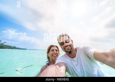 Heureux l'homme et de la femme en tenant dans les selfies mer des Caraïbes. Mi adultes voyageant en couple, les gens s'amuser en vacances. Banque D'Images