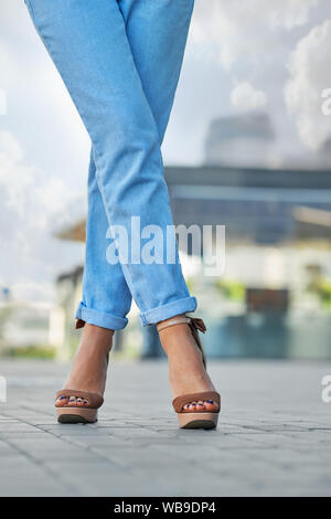 Femelle croisé les jambes en jean bleu et des chaussures en daim sur le pavé Banque D'Images