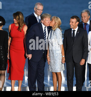 Le président français, Emmanuel Macron regarde sa femme Brigitte Macron baisers Président Donald Trump comme il se tient avec la première dame Melania Trump comme ils inscrivez-vous d'autres dirigeants du monde pour la photo de famille au sommet du G7 à Biarritz, France. Banque D'Images