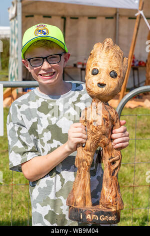 Knutsford, Cheshire, Royaume-Uni. 25 août 2019. La 15e English Open Chainsaw compétition à la Cheshire County Showground, Angleterre - Jeune garçon est titulaire d'une sculpture d'un personnage de 'Groot' sculpté par John Hayes de l'Irlande Crédit : John Hopkins/Alamy Live News Banque D'Images