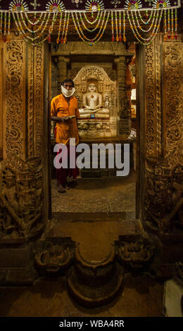 Un homme se tient dans la chambre intérieure de ce temple de Jain en tenant les offres monétaires dans un temple Jain au sein de Fort Jaisalmer, Inde. Banque D'Images