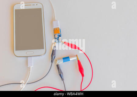 Le chargeur de téléphone portable à partir de la batterie 1,5 V, chargeur de batterie, circuit board, cordon d'alimentation, multi-usages, sur le fond blanc.Comment faire par yo Banque D'Images