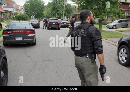 Service de police de Detroit, officier des opérations spéciales tiroirs son arme alors qu'il se prépare à aborder une maison, qu'ils en ont l'air d'un suspect, Detroit, Michigan, USA Banque D'Images