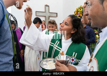 J'ai été ordonné pasteur luthérien donne une plaquette de la communion à un membre de la congrégation pendant le service à l'Église luthérienne de la résurrection à San Salvador, El Salvador. Banque D'Images