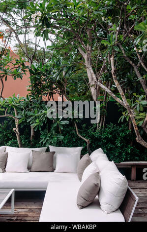 AUG 7 2014, Hua Hin, Thaïlande - vacances tropicales balcon en bois avec tissu blanc canapé lit et oreillers sous l'arbre vert luxuriant et de plantes tropicales b Banque D'Images