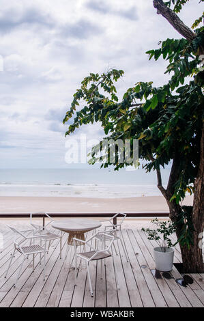 AUG 7 2014, Hua Hin, Thaïlande - vacances tropicales. Seaview balcon en bois avec table et chaise design bien sous grand arbre par jour nuageux dans la région de Rainy seaso Banque D'Images