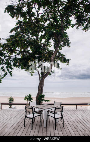 AUG 7 2014, Hua Hin, Thaïlande - vacances tropicales. Seaview balcon en bois avec chaise et table sous grand arbre par jour nuageux dans la saison des pluies Banque D'Images