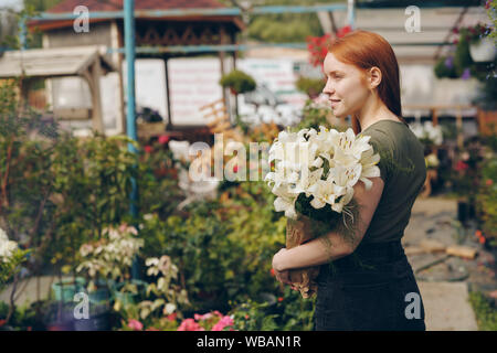 Belle rousse Smiling girl holding lis dans sac de papier Banque D'Images