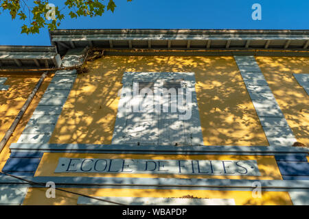 Façade de l'école jaune sur lequel il est écrit en français sur le dessus d'une porte d'entrée "pour les filles", des roches-de-Condrieu, France Banque D'Images
