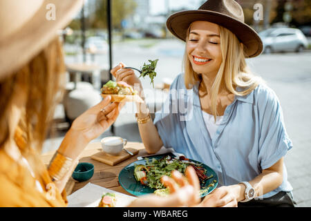 Les deux meilleurs amis de manger des aliments sains tout en étant assis sur une terrasse de restaurant un jour d'été Banque D'Images