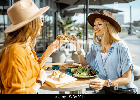 Les deux meilleurs amis de manger des aliments sains tout en étant assis sur une terrasse de restaurant un jour d'été Banque D'Images