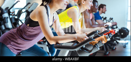 Femme asiatique et ses amis sur vélo de fitness en salle de sport Banque D'Images