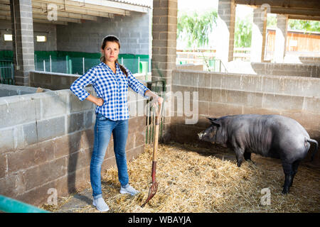 Portrait of female farmer nourrir les porcs ibériques sur farm Banque D'Images