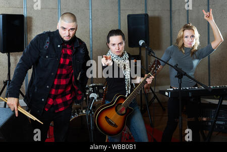 Portrait de groupe de musiciens rock expressif posant avec instruments en studio d'enregistrement Banque D'Images