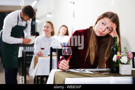 Femme élégante en colère s'attend à ce que l'homme pour le dîner dans le restaurant de luxe intérieur. Banque D'Images