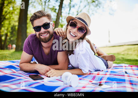 Cute young couple smiling and looking at camera while lying on a Blanket et profiter de l'été Banque D'Images