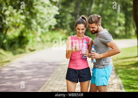 Jeune couple à la recherche de téléphone pendant la course à l'été Banque D'Images