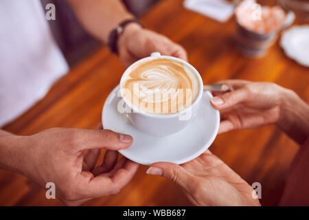 Close-up de café avec latte art accordée à la clientèle féminine par barista Banque D'Images