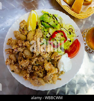 Vue de dessus de Chipirones Tapa traditionnel espagnol - peu de calamars en pâte servi avec une salade de légumes frais, citron et sauce crémeuse Banque D'Images