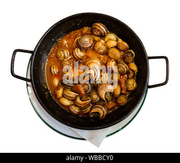 Vue de dessus du poêle noir avec Tapa traditionnel espagnol Caracoles en salsa - compotée d'escargots en sauce faite maison. Plus isolé sur fond blanc Banque D'Images