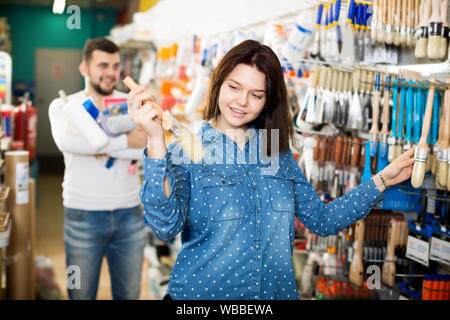 Smiling couple d'examiner diverses brosses de peinture en magasin de fournitures de peinture Banque D'Images