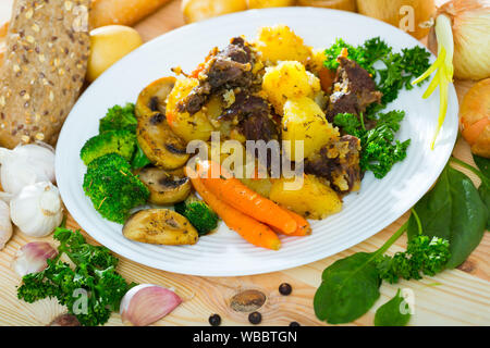 Ragoût de boeuf aux appétissantes pommes de terre, champignons et légumes servi sur plaque blanche Banque D'Images