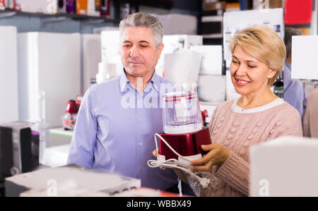 L'homme et la femme 47-57 ans sont l'achat en boutique d'électroménager et de l'extracteur de jus broyeur pour elle-même à la maison. Banque D'Images