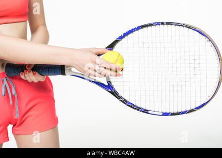 Portrait d'une femme confiante et raquette tennis player holding ball sur fond gris Banque D'Images