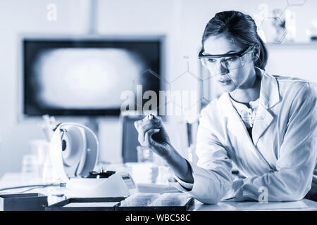 Portrait d'une femme confiante chercheur en laboratoire des sciences de la vie de structure d'écriture formule chimique sur un verre. Banque D'Images