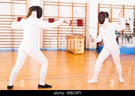 Deux femmes tireurs pratiquant des techniques en duel à l'entraînement de l'escrime Banque D'Images