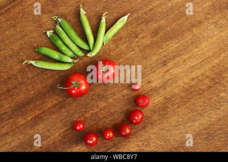 Vue de dessus de produits frais bio légumes cultivés sur une table en bois brun. tomates, concombres et les pois with copy space Banque D'Images