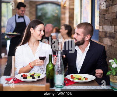 Les jeunes hommes et femmes couple célébrant anniversaire avec de la nourriture et du vin Banque D'Images