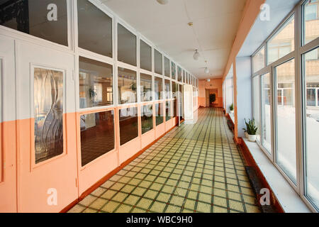 Vue à l'intérieur du corridor d'entrée , la vieille école ou immeuble, impasse longue et étroite passerelle et fenêtre en verre orange tôt le matin avec shi Banque D'Images