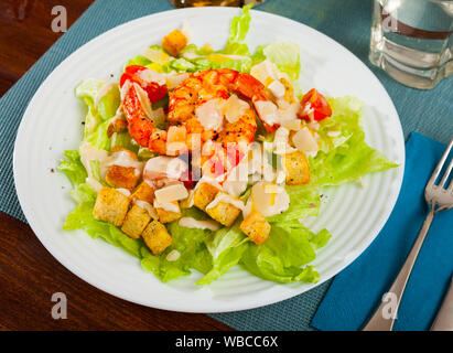 Délicieux salade César de laitue romaine et de croûtons recouverts de sauce délicate garnie de crevettes et parmesan Banque D'Images