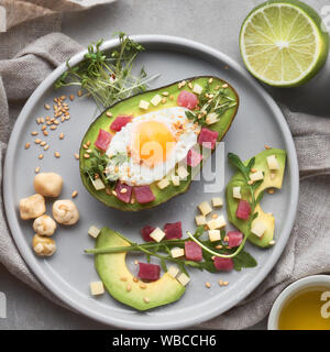 Régime céto lave : au four avec des cubes de jambon bateau Avocat, oeuf de caille et fromage servi avec salade de roquette vert, plat déposer sur la pierre grise avec des ingrédients Banque D'Images