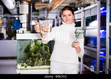 Teenage girl holding est poissons verseau net et bac à eau avec de gros poissons à l'intérieur orange ondulé. Banque D'Images