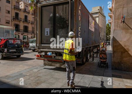 Barcelone, Espagne. Août 26, 2019. Un opérateur surveille l'approche du chariot avec le premier conteneur de logement.conférence de presse pour l'installation du premier module conteneur du projet (APROP) hébergements temporaires pour les familles sans abri et sur la liste d'attente. Une fois que la construction est terminée, autour d'octobre 2019, l'édifice sera temporairement chambre douze familles sans ressources. La loi a été présenté par le conseiller Laura Pérez et le conseiller du district du district de Ciutat Vella, Jordi Rabassa. Credit : SOPA/Alamy Images Limited Live News Banque D'Images