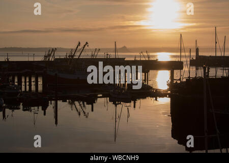 Silhouettes de bateaux dans le port de Newlyn, Cornwall, au lever du soleil avec St Michael's Mount en arrière-plan Banque D'Images
