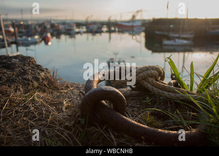 Chaîne d'amarrage rouillées au lever du soleil avec le port de Newlyn en arrière-plan, paysage Banque D'Images