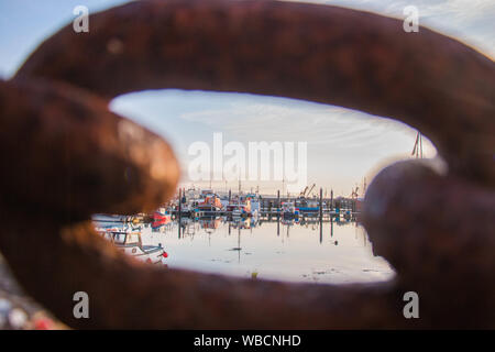 Bateaux dans le port de Newlyn, Cornwall, vue par le biais de link en grande chaîne de fer rouillé Banque D'Images