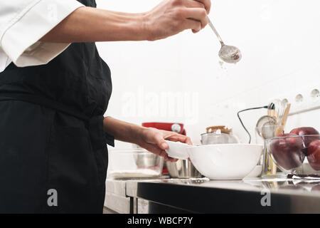 Photo recadrée d'un beau jeune cuisinier chef à la cuisine la cuisson à l'intérieur. Banque D'Images